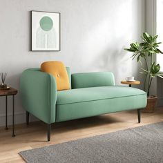 a living room with a couch, table and potted plant on the floor next to it