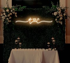 the table is set up with white linens and greenery, along with candles