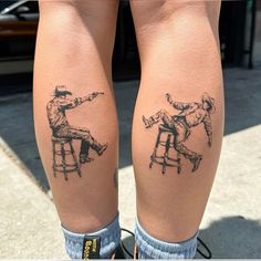 two people sitting on stools with tattoos on their legs, one is pointing at the other