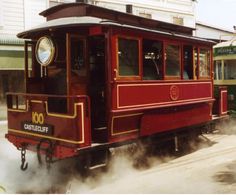 a red trolley car traveling down train tracks