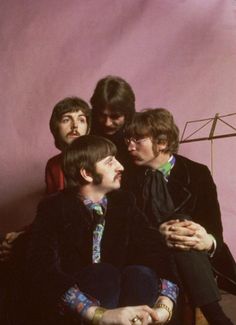 the beatles posing for a photo in front of a pink background