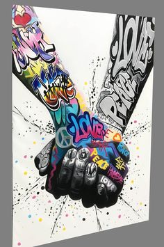 two hands holding each other with colorful graffiti on the wall behind them and below it