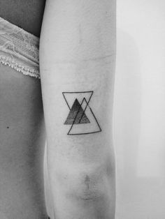 a black and white photo of a woman's arm with a triangle tattoo on it