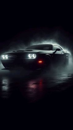 a black car in the dark with fog coming out of it's back end