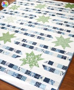 a quilted table runner with green and blue stars on the top, sitting on a wooden floor