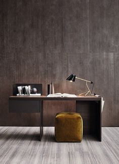 a desk with a lamp, books and a book on it in front of a wall