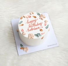 a birthday cake with flowers and leaves on it sitting on top of a white tablecloth