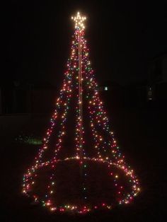 a lighted christmas tree in the middle of a yard