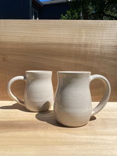 two white mugs sitting on top of a wooden table