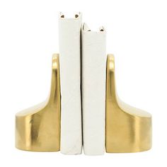 two white and gold bookends sitting side by side on top of each other