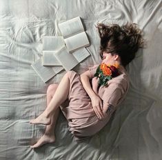 a woman laying on top of a bed with an open book next to her face