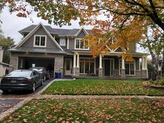 a car parked in front of a house with autumn leaves on the grass and trees