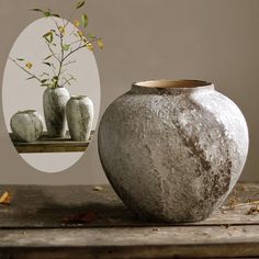 a vase sitting on top of a wooden table next to three small vases with flowers in them