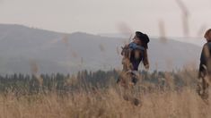 two children are walking through tall grass in the mountains