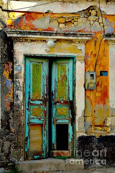 an old building with two green doors and peeling paint