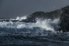 some birds are flying over the waves in the ocean