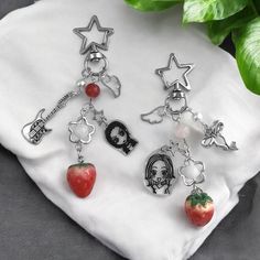 four charms are sitting on top of a white cloth next to a green plant and a red strawberry