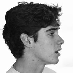 a black and white photo of a young man with curly hair wearing a collared shirt