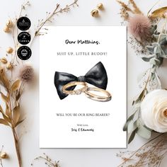 a card with two wedding rings on it next to some flowers and greenery that says dear nothing, suit up little buddy