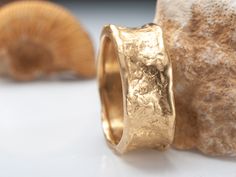 a gold ring sitting on top of a white table next to a rock and shell