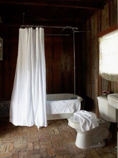 a bathroom with a toilet, sink and bathtub next to a shower curtain in the corner