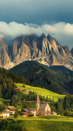 the mountains are covered in clouds and green grass, while houses stand on either side