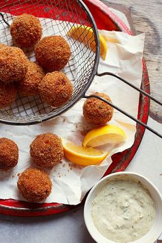 some food is sitting on a red tray and next to a bowl of dipping sauce