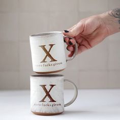 two coffee mugs are stacked on top of each other with the letter x printed on them