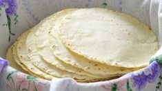 a basket filled with tortillas sitting on top of a purple and white cloth