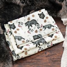 the blanket has bears on it and is next to a teddy bear scarf with pom poms