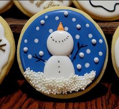 decorated cookies with frosting and icing are arranged on a wooden surface, including one snowman