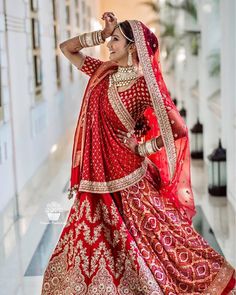 a woman in a red and gold bridal gown posing for the camera with her hands on her head