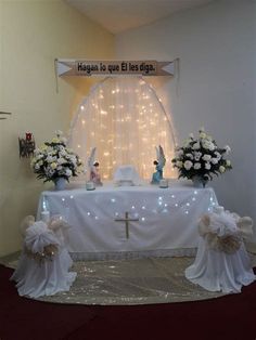 a table with flowers and candles on it in front of a wall decorated with lights