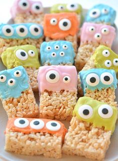 rice krispy treats decorated like monsters and eyes are on a white plate with other food items in the background