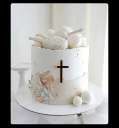 a white cake with an angel figurine sitting on it's side next to a cross