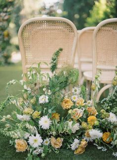 an arrangement of flowers on the ground next to chairs