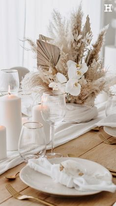 the table is set with white dishes and candles