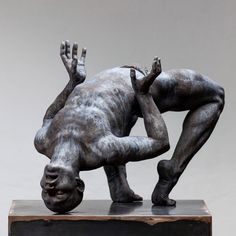 a statue of a man bending over on his back with one hand in the air