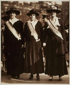 three women in long dresses and hats are posing for a photo while wearing sashs