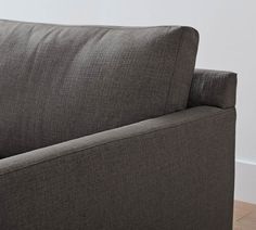 a gray couch sitting on top of a hard wood floor next to a white wall