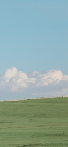 two giraffes standing in the middle of a large open field with clouds