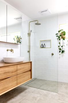 a bathroom with a sink, mirror and shower in it's center wall next to a wooden cabinet