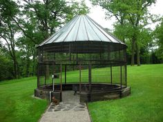 a gazebo sitting on top of a lush green field next to a stone walkway