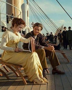 a man and woman sitting on a bench next to each other in front of a boat