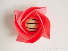 an origami flower on a white wall with the center cut out to look like a ball