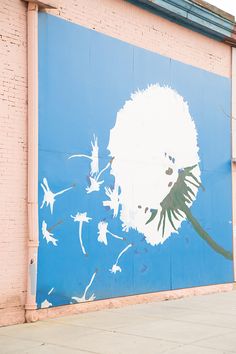 a mural on the side of a building with a dandelion painted on it