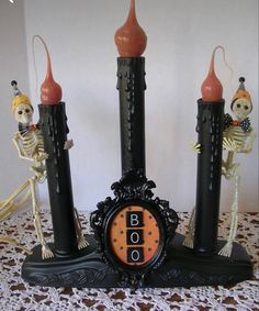 a clock that is sitting on top of a table with skeleton candles in front of it