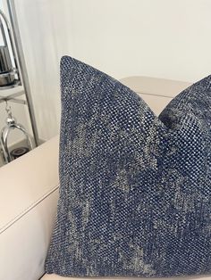 a blue and white pillow sitting on top of a couch next to a wall mounted mirror