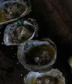 several oysters on a cutting board with an apple in the background