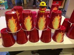 red cups with yellow flames on them are sitting on a table in front of other items